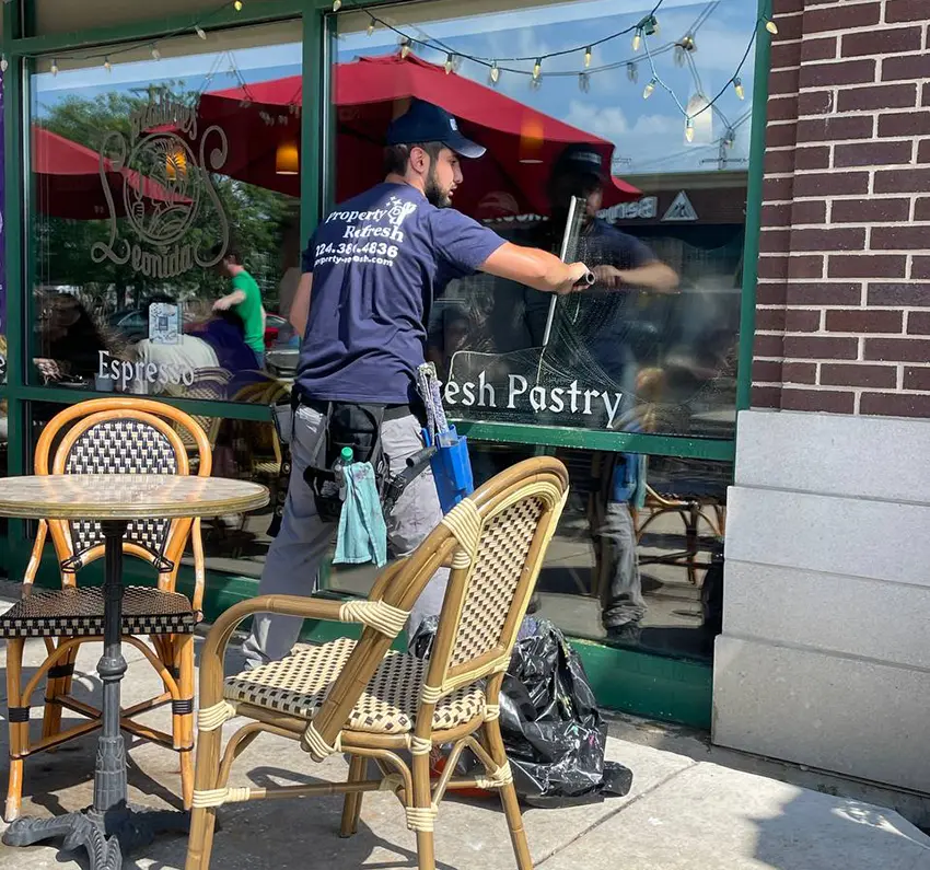 man cleaning windows in a coffee shop